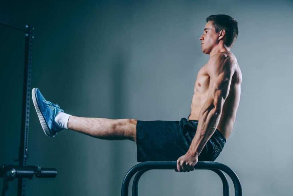 man performing advanced bodyweight exercise hold on parallel bars demonstrating full body strength