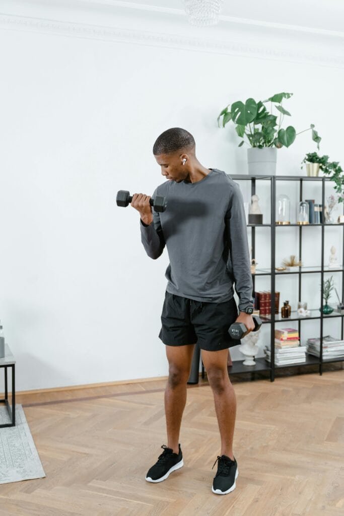 man performing dumbbell bicep curl at home as part of an intense workout plan