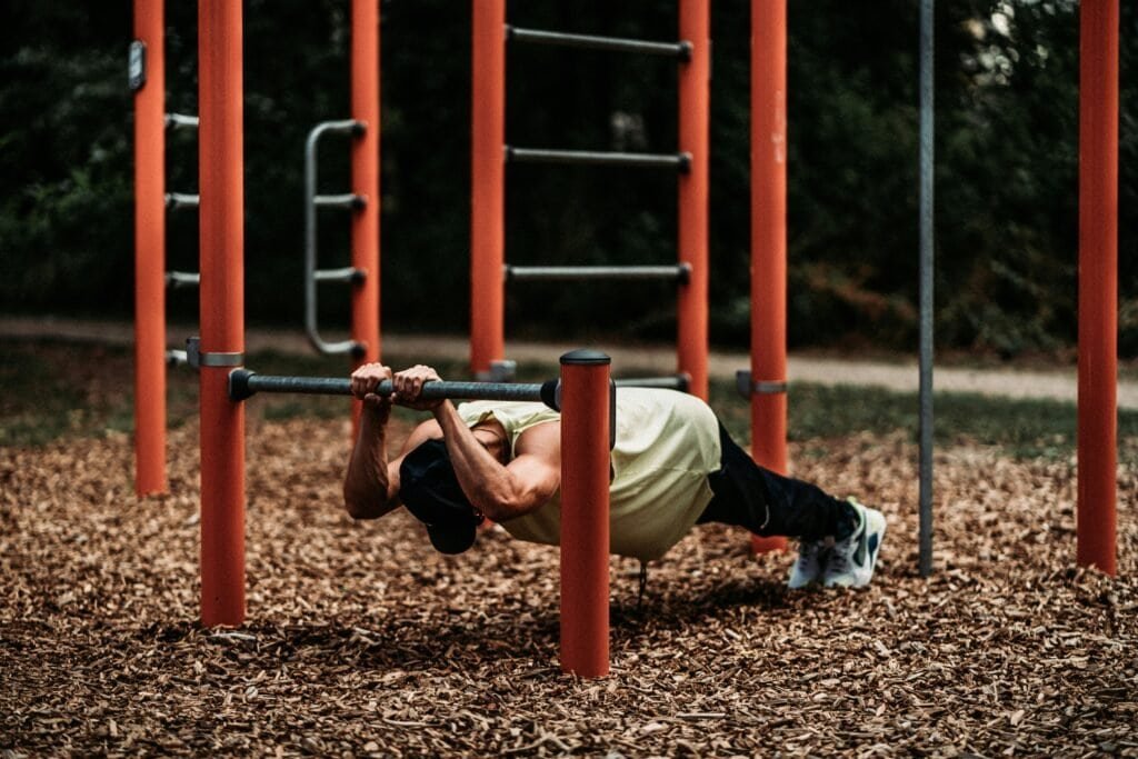 person performing bodyweight triceps exercise on a low bar to stimulate muscle hypertrophy
